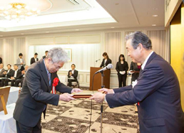 President and Representative Director Yuji Kaneko receiving the plaque